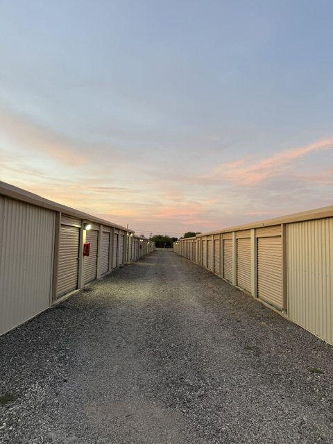 A clean lane of drive-up storage units with maroon roll-up doors